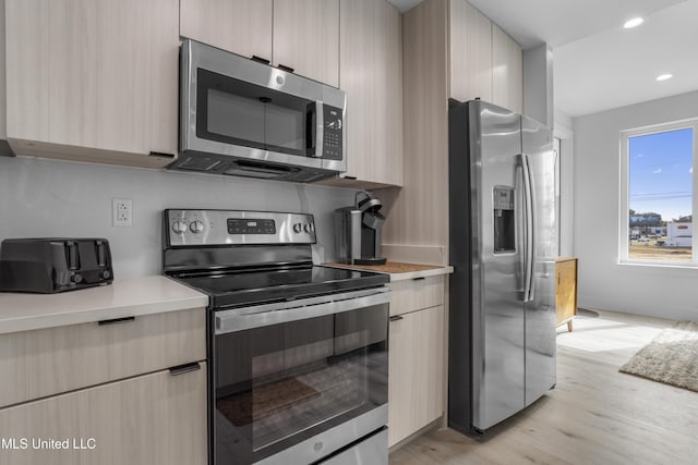 kitchen featuring stainless steel appliances, modern cabinets, and light countertops