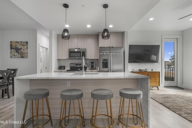 kitchen with decorative light fixtures, stainless steel appliances, a spacious island, light wood-style flooring, and modern cabinets