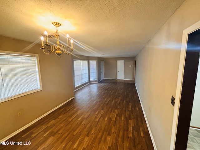 spare room featuring a chandelier, a textured ceiling, and dark hardwood / wood-style flooring