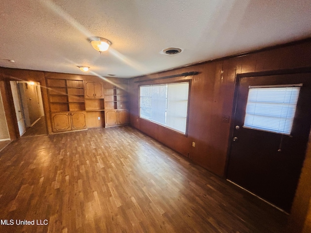 interior space with hardwood / wood-style flooring, a textured ceiling, and wooden walls