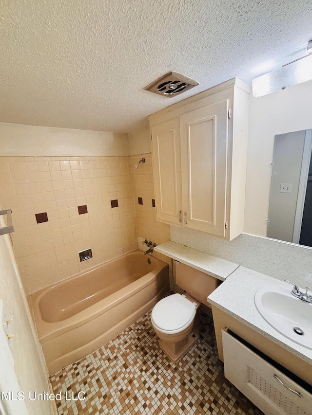 full bathroom with toilet, tiled shower / bath combo, vanity, and a textured ceiling