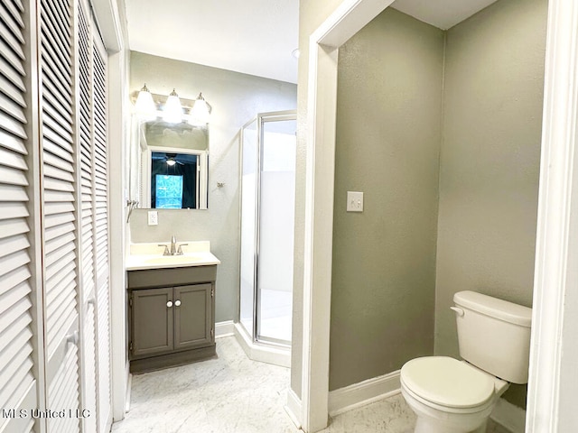 bathroom featuring a shower with door, vanity, and toilet