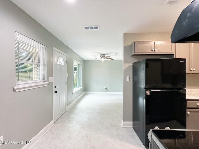 kitchen featuring a wealth of natural light, ventilation hood, ceiling fan, and black fridge