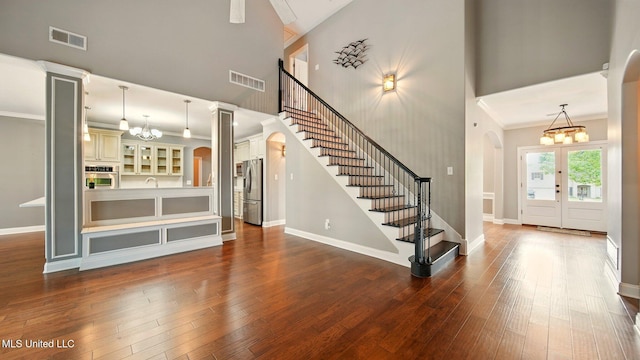 entrance foyer with stairway, hardwood / wood-style flooring, a chandelier, ornamental molding, and a towering ceiling