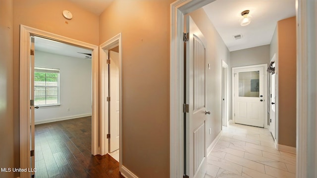 hallway featuring baseboards and marble look tiles