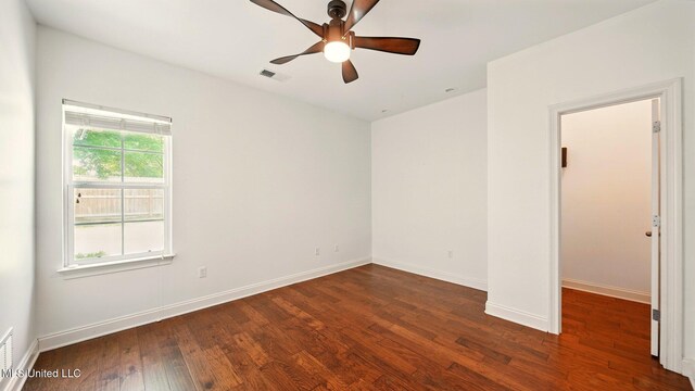 empty room featuring wood finished floors, baseboards, and ceiling fan