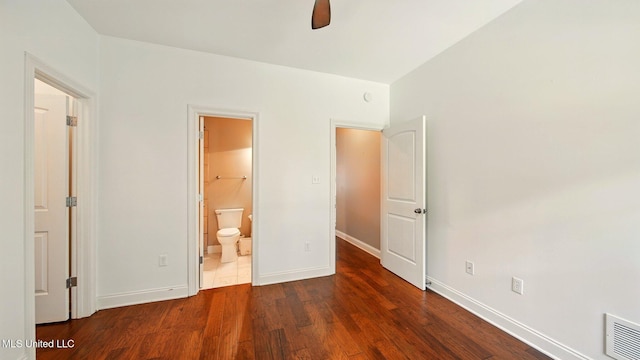 unfurnished bedroom with wood finished floors, baseboards, and connected bathroom