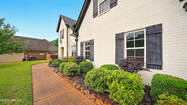 view of side of property featuring a lawn and brick siding