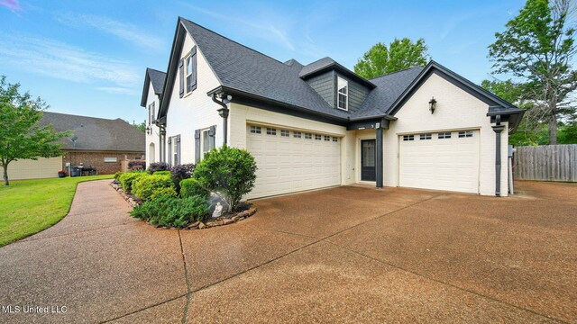 view of front facade with driveway, brick siding, fence, a shingled roof, and a garage