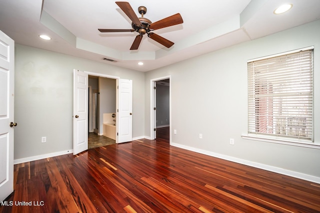 unfurnished bedroom with ceiling fan, dark hardwood / wood-style flooring, ensuite bathroom, and a tray ceiling