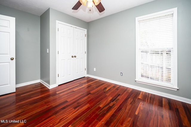 unfurnished bedroom with ceiling fan, a closet, and dark wood-type flooring