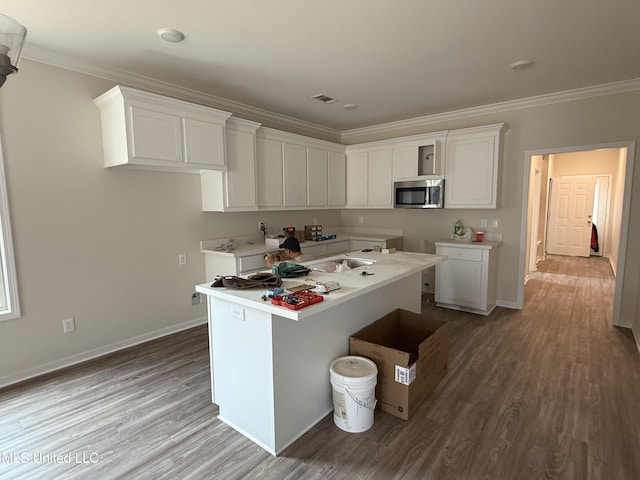 kitchen with ornamental molding, a kitchen island with sink, white cabinets, and light wood-type flooring