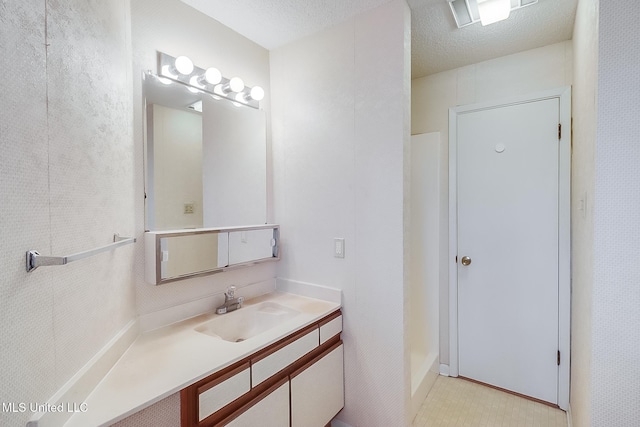 bathroom featuring a shower, vanity, and a textured ceiling