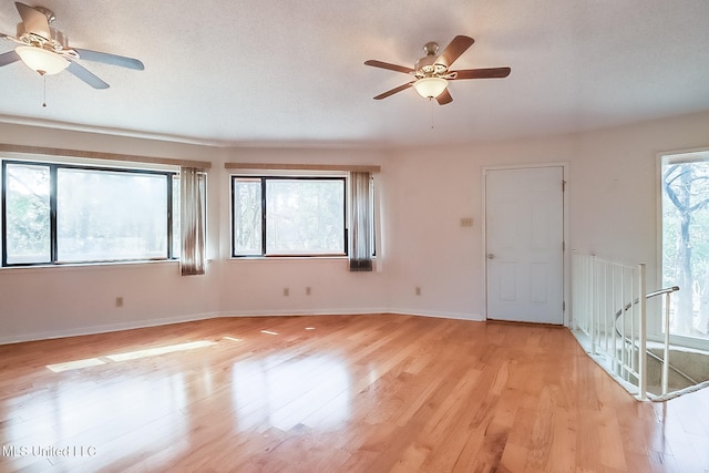 spare room with ceiling fan, plenty of natural light, and light hardwood / wood-style flooring