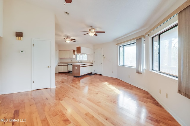 unfurnished living room featuring sink, ceiling fan, and light wood-type flooring