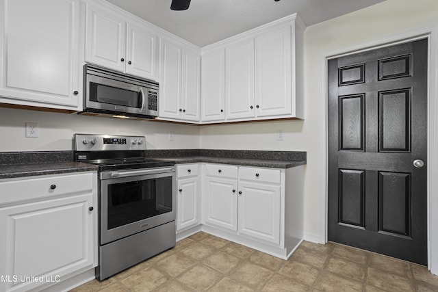 kitchen featuring appliances with stainless steel finishes, white cabinets, dark countertops, and ceiling fan