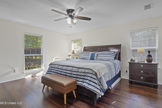 bedroom featuring a textured ceiling, visible vents, baseboards, and hardwood / wood-style flooring