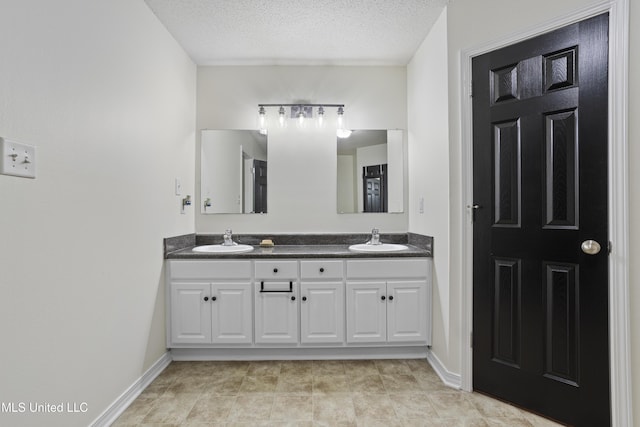 bathroom with baseboards, a sink, and a textured ceiling