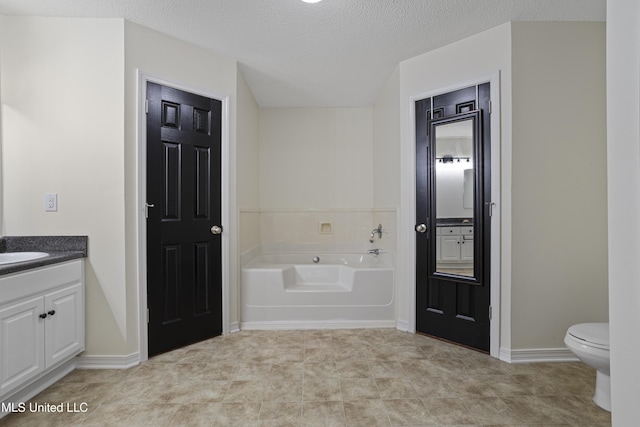 bathroom with vanity, a textured ceiling, toilet, and a bath