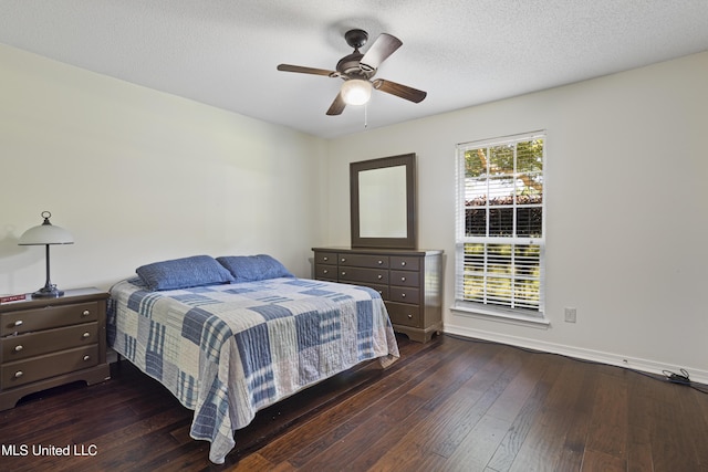 bedroom featuring baseboards, ceiling fan, dark wood finished floors, and a textured ceiling