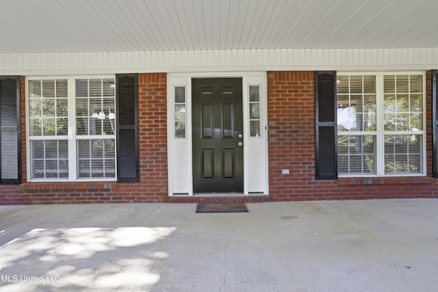 property entrance featuring a porch and brick siding
