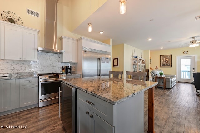 kitchen with a breakfast bar area, dark wood-type flooring, hanging light fixtures, stainless steel appliances, and beverage cooler