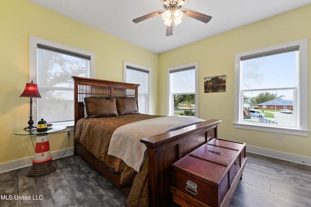 bedroom with ceiling fan, multiple windows, and dark hardwood / wood-style floors