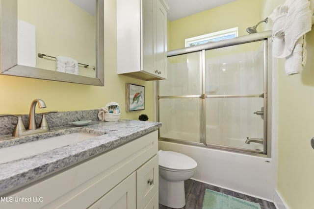 full bathroom featuring shower / bath combination with glass door, vanity, wood-type flooring, and toilet