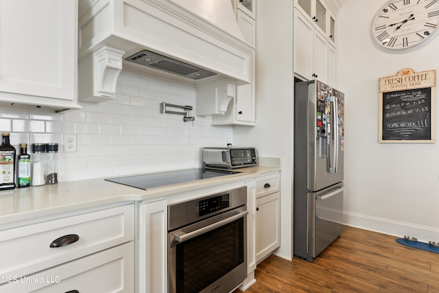 kitchen with white cabinetry, stainless steel appliances, custom range hood, dark hardwood / wood-style flooring, and decorative backsplash