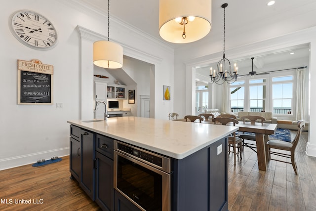 kitchen with sink, ornamental molding, dark hardwood / wood-style floors, a notable chandelier, and a kitchen island with sink