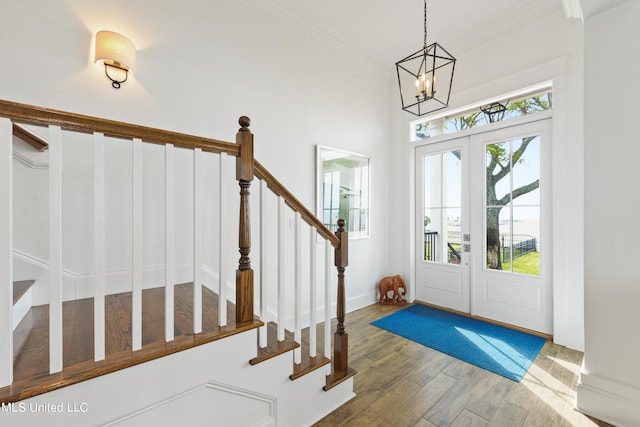 foyer entrance with french doors, ornamental molding, dark hardwood / wood-style flooring, and a chandelier