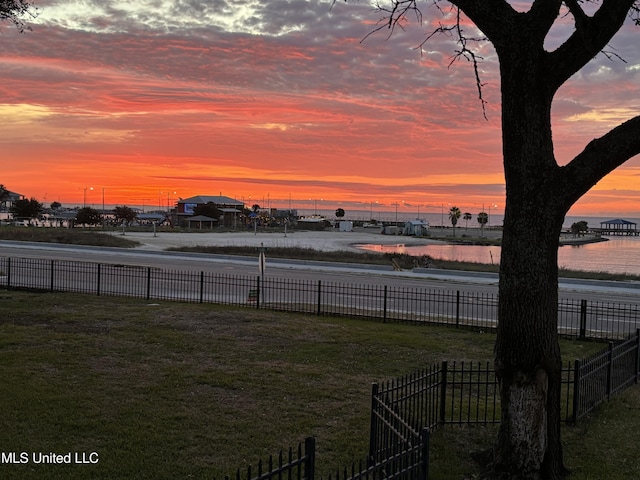 yard at dusk featuring a water view