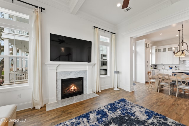 living room with crown molding, ceiling fan with notable chandelier, and dark wood-type flooring