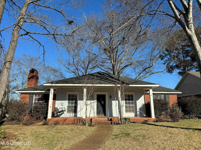 view of front of property featuring a chimney, a front lawn, a porch, and brick siding