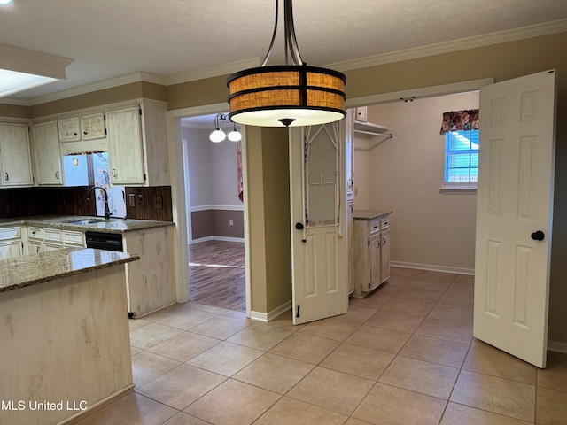 kitchen with light tile patterned floors, ornamental molding, a sink, and light stone counters