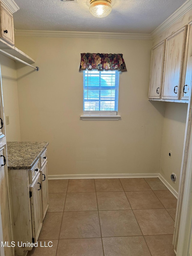 laundry area with cabinet space, a textured ceiling, crown molding, and light tile patterned flooring