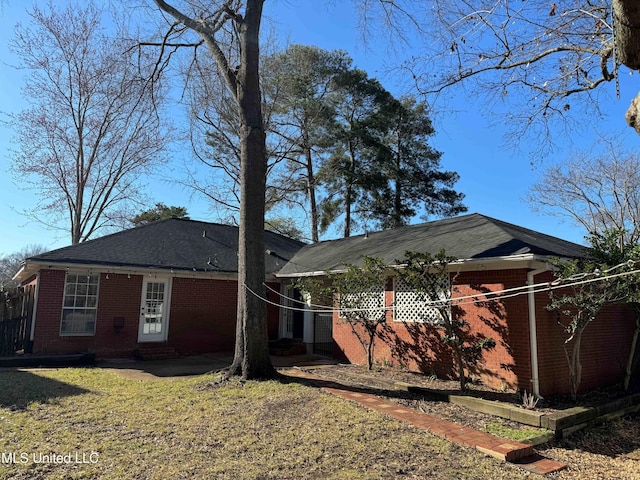 rear view of house with brick siding, a yard, and a patio