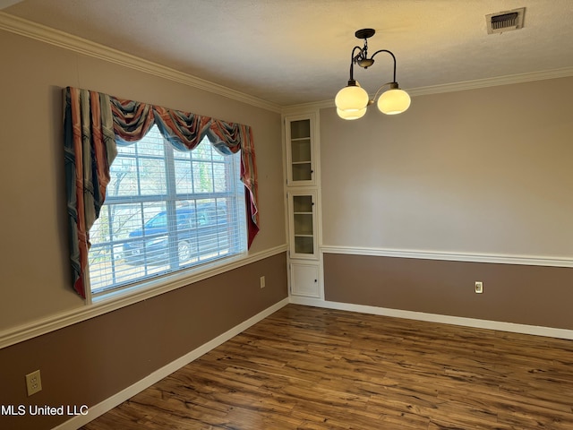 unfurnished room with dark wood-style flooring, crown molding, visible vents, an inviting chandelier, and baseboards