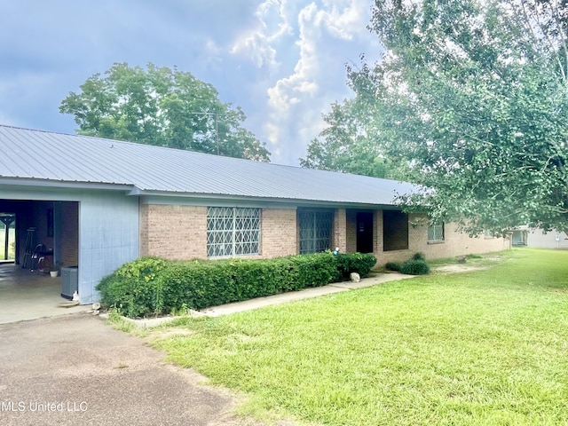 ranch-style house featuring metal roof, central AC unit, a front lawn, and brick siding