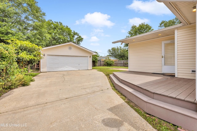 view of patio featuring a detached garage, fence, an outdoor structure, and a deck