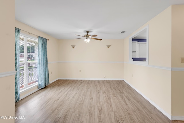 empty room featuring ceiling fan, visible vents, baseboards, and light wood-type flooring