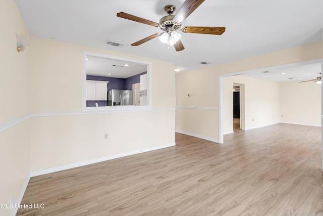 empty room featuring light wood-style floors, baseboards, ceiling fan, and visible vents