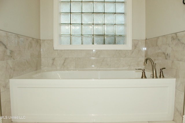 bathroom featuring a bathing tub, tile walls, and a healthy amount of sunlight