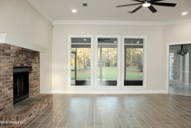 unfurnished living room with hardwood / wood-style flooring, ceiling fan with notable chandelier, crown molding, and a brick fireplace