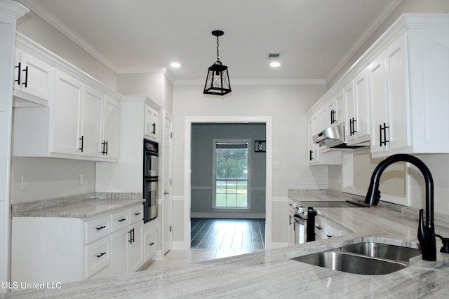 kitchen with pendant lighting, white cabinets, sink, double oven, and light hardwood / wood-style floors