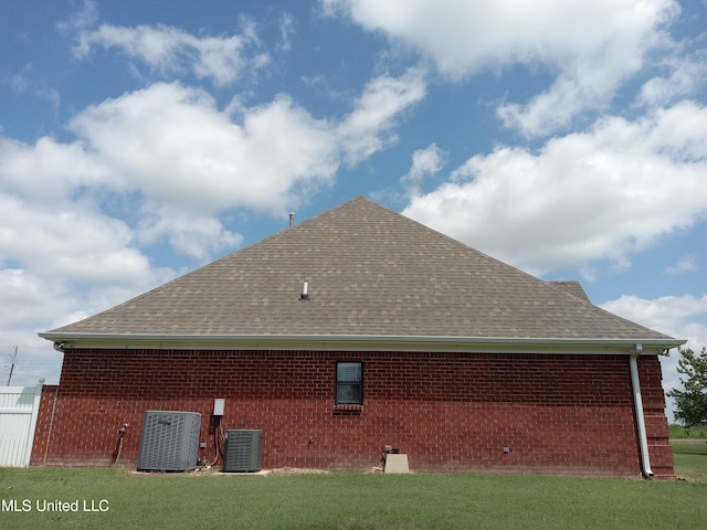 496 Cleveland Crossing Rd, Cleveland, MS 38732 - view of side of home with a shingled roof, cooling unit, brick siding, and a yard