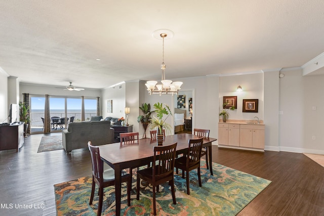 dining room featuring baseboards, dark wood-type flooring, ornamental molding, and ceiling fan with notable chandelier