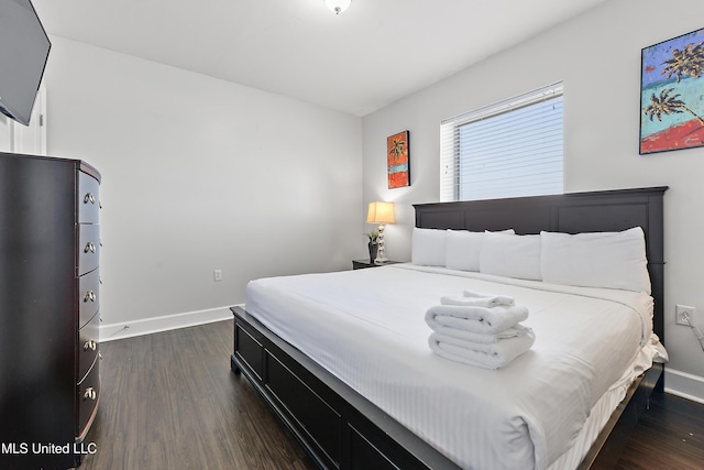 bedroom featuring baseboards and dark wood-style flooring