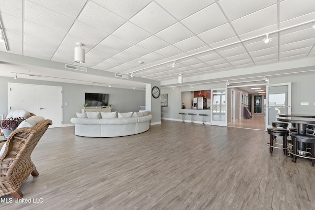 living room featuring visible vents, a drop ceiling, track lighting, and wood finished floors