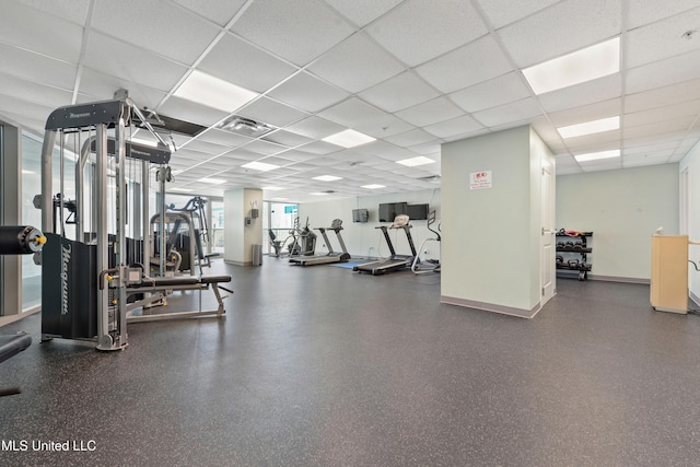 exercise room with a paneled ceiling, visible vents, and baseboards